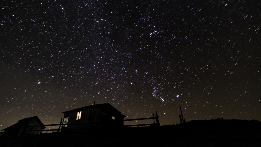 Time lapse of Star trails over Wooden house in the night sky. 4K