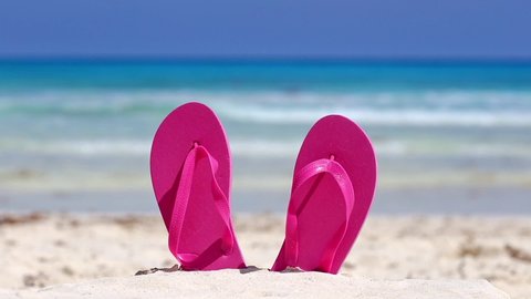Pink flip flops on white sandy beach near caribbean sea, nobody. Summer vacations
