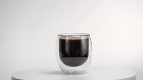  Black coffee in transparent, glass cup. Glass with black coffee on white background. Empty place for text. Marketing, advertising use. Looping video. 