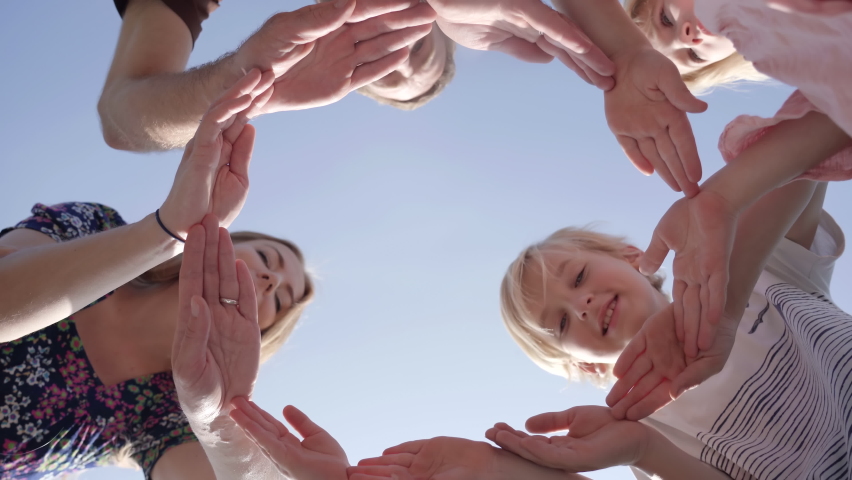 A friendly family makes a circle out of their hands and looks into it. Royalty-Free Stock Footage #1062546976