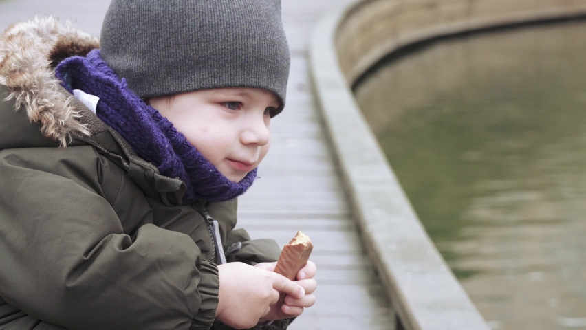 Boy eating chocolate energy bar on the street