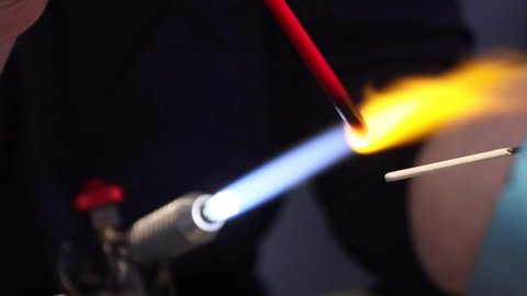 Heating the glass billet with a gas burner. The process of making glass jewelry. Close-up of the flame.4K