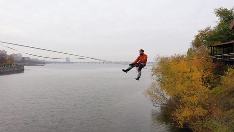 Man balancing on slackline over the river. Falling from slackline

