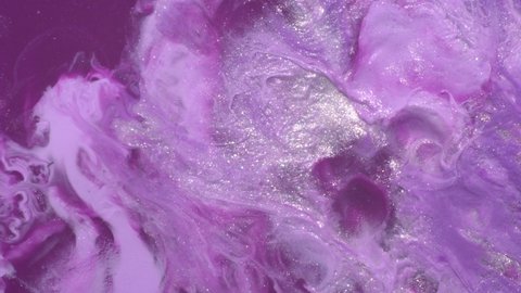 Purple, pink, pastel lilac, silver, shiny white pearl colors mix. Paint movement macro. Ink flow. Glitter fluid motion. Moving flowing stream of liquid paint. Beautiful abstract background