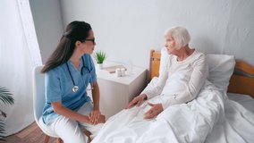 aged woman gesturing while lying in bed and talking to doctor