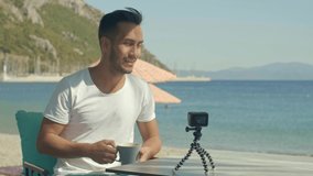 A man filming a video with a tiny camera. Young man who makes a travel program tells the places she visits to the camera.