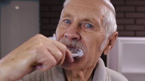 Cheerful old senior man grandfather in bathrobe brushing teeth and looking into mirror. Handsome elderly grandpa doing morning hygiene after shower at luxury bathroom at home. Point of view. POV shot - Powered by Shutterstock - Get 15% off with code: PIKWIZARD15