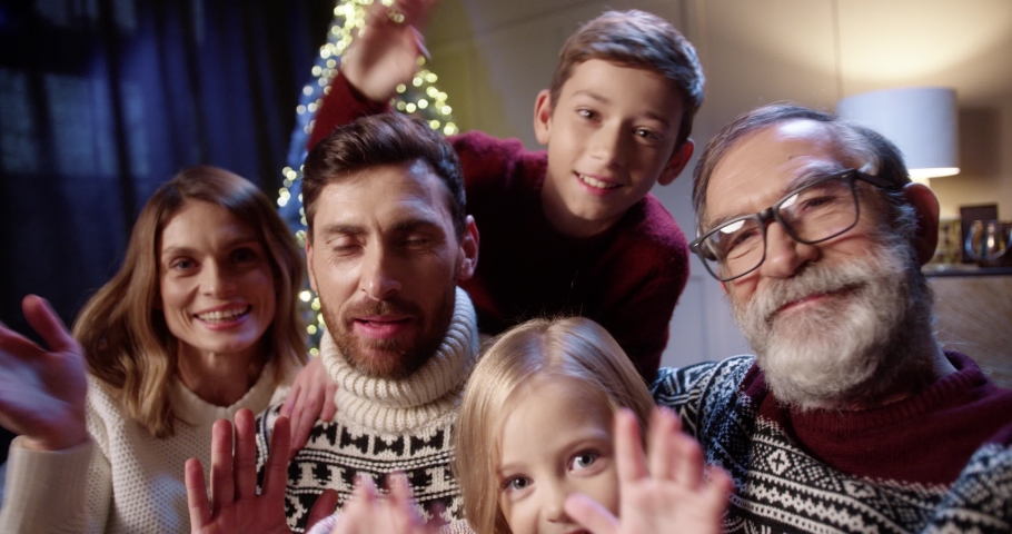 POV f joyful lovely Caucasian family with kids gathered together in cozy room with glowing xmas tree and video chatting online sending holiday greetings to friends Happy holidays concept | Shutterstock HD Video #1062570979