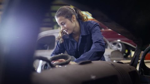 4K Attractive female mechanic working on car engine in garage workshop