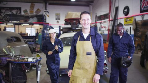 4K Portrait of cheerful team of male and female mechanics in garage workshop