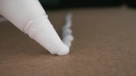 Man applies PVA glue to cardboard. Close-up. The camera moves with the glue tube