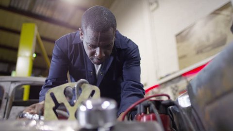 4K Mechanic working on a classic car engine in garage workshop