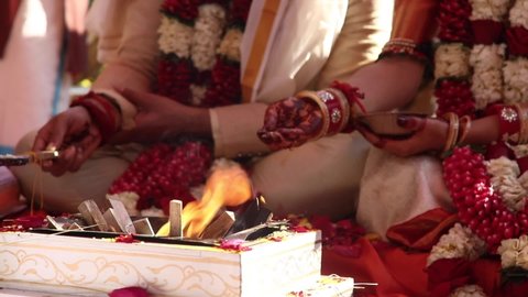 Traditional Indian hindu wedding ceremony infront of holy fire in a temple. bride and groom henna hands close up. beautiful kurta and sari. day time ritual.