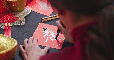 back view of asian woman write Chinese festival couplet to celebrate new year with word meaning spring