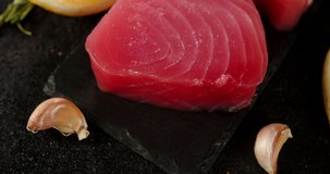 Raw tuna steak on a stone board. On a black background. High quality 4k footage