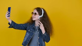 Happy girls in sunglasses with headphones smiling and posing while making selfie on the phone. lifestyle and joyful people concept.