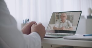 psychologist is explaining to male elderly patient during online appointment, closeup of doctor hands and screen