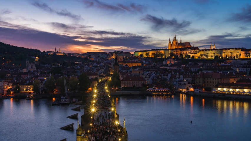 Prague, Czech Republic, zoom in time lapse view of Prague cityscape at sunset including historical landmarks Prague Castle and Charles Bridge in autumn season.