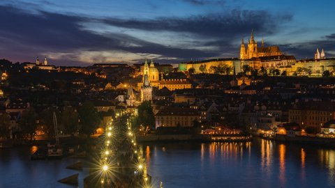 Prague, Czech Republic, zoom in time lapse view of Prague cityscape at sunset including historical landmarks Prague Castle and Charles Bridge in autumn season.