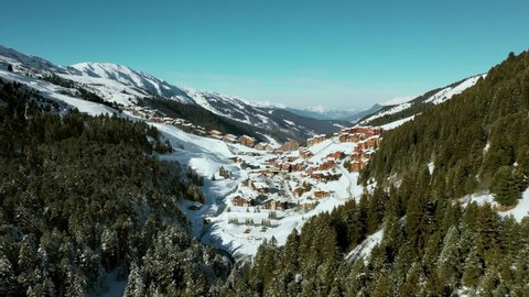 Aerial: amazing Val Thorens ski resort chalets on mountainside, sunny day