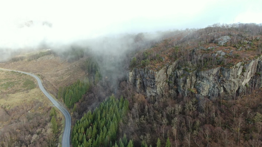 Aerial View of Scenic Landscape and Morning Fog Above Cliffs, Forest and Road in Rural Norway