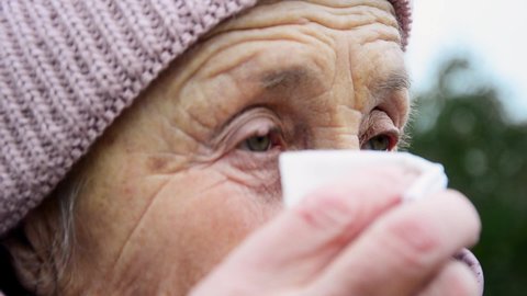 Close-up of wrinkled face of old grandmother. Grandma looking forward with hope. Elderly woman concept. Aged parents. Tears of an old woman close up. Grandmother wipes her eyes from tears. 