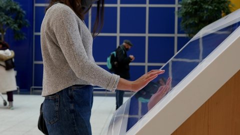Woman looking for information and location of shopping place on digital touch screen in shopping mall