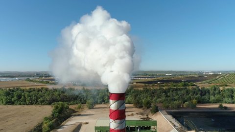 4K 60 fps steady aerial shot. Smoking chimney or smokestacks of a factory. Air contamination concept. Slow-motion footage of the rising smoke or steam.