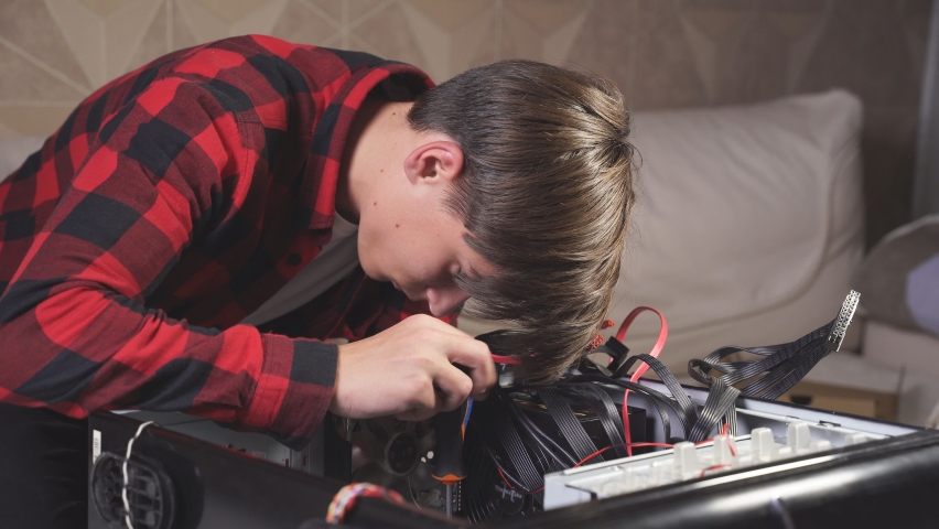 young man is fixing his computer at home. Computer repair. The teenager understands the computer. Royalty-Free Stock Footage #1062624610