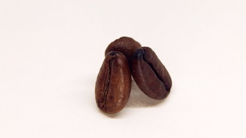 Three roasted coffee beans rotating macro