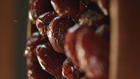 In a beautiful light, dried date fruit fall into the wooden plate in slow motion. 4K,Very close up, phantom camera,900 fps video.Video for the vertical story.