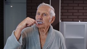 Cheerful old senior man grandfather in bathrobe brushing teeth and looking into mirror. Handsome elderly grandpa doing morning hygiene after shower at luxury bathroom at home. Point of view. POV shot - Powered by Shutterstock - Get 15% off with code: PIKWIZARD15