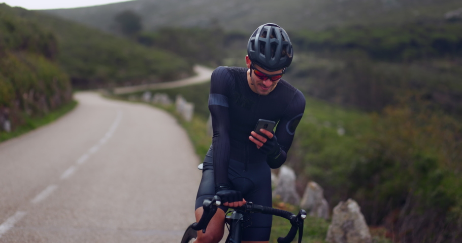 Professional cyclist checking smartphone on sports bicycle on a mountain | Shutterstock HD Video #1062627991