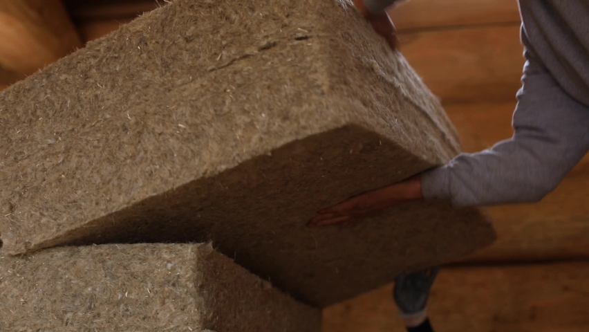 Close up of men's hands lifting a pair of thick hemp wool sheets from a pile, in the building site of an eco friendly house in construction. Royalty-Free Stock Footage #1062630196