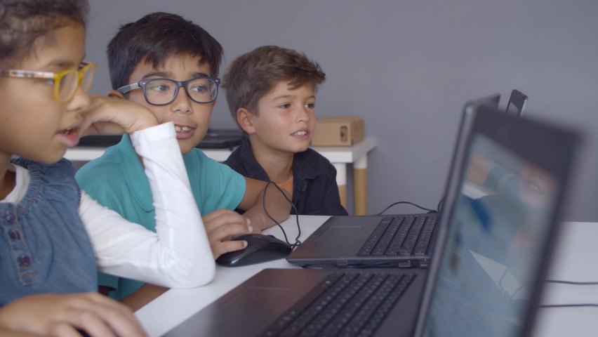 Schoolchildren doing task together, helping each other, using laptops during computer science class. Side view. Digital education and teamwork concept Royalty-Free Stock Footage #1062637612