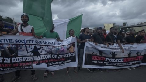 Port Harcourt, Nigeria - October 20, 2020: Crowd of protesters walking around the city of Port Harcourt raising placards and signs for the #Endsars protests in Nigeria and singing to a popular song 