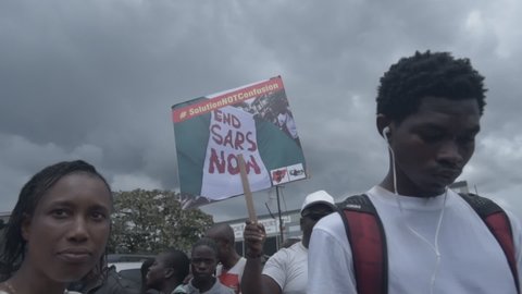 Port Harcourt, Nigeria - October 20, 2020: Crowd of protesters walking around the city of Port Harcourt raising placards and signs and chanting End Sars.