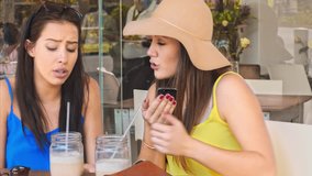4k medium video of multicultural woman friends using smartphones and drinking iced coffee refreshment at cafe.  