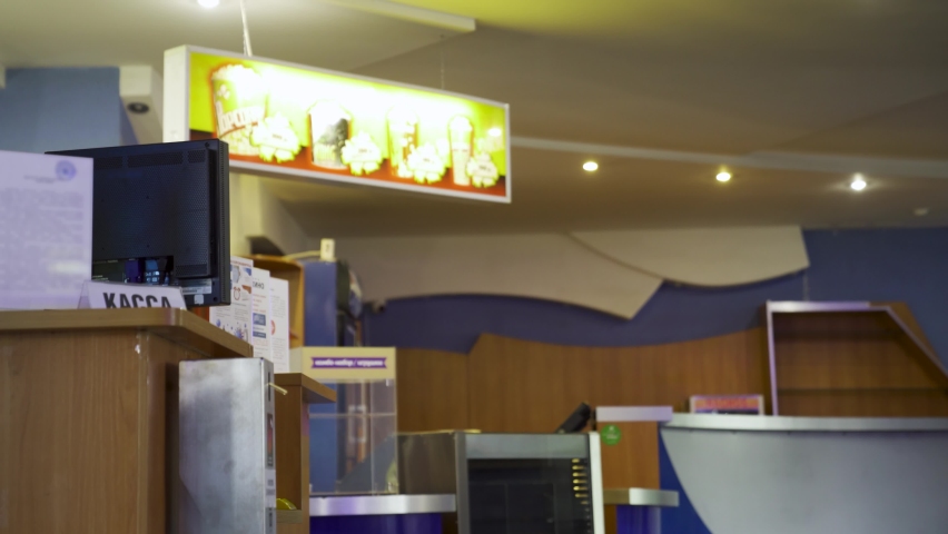Side view of a young man buying the movie tickets at the movie theater hall. Media. Male in medical mask paying for cinema tickets, concept of leisure.