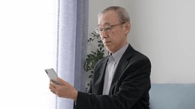 asian senior man talking video chat to using smart phone at living room