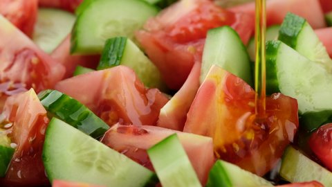 pour olive oil on vegetables salad with tomatoes and cucumbers. healthy food