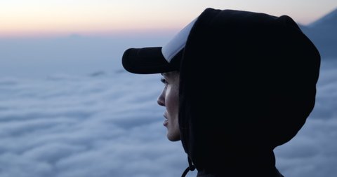 Young woman enjoying view from outlook during hike in mountains.Above the clouds