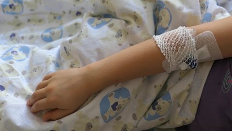 Peripheral Venous Catheter on Young Girl Patient Arm in Hospital Bed