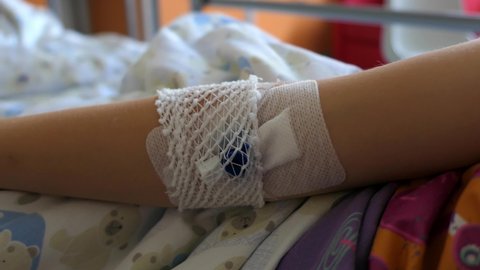 Peripheral Venous Catheter on Young Girl Patient Arm in Hospital Bed