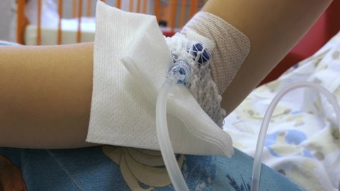Young Girl on a Drip with Peripheral Venous Catheter in Hospital Bed