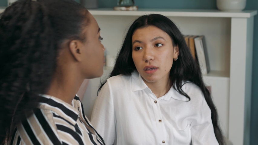 Loving caring beautiful black female talking to upset depressed young asian friend, caring girl giving support advise understanding empathy to stressed adult hispanic woman. Serious conversation  Royalty-Free Stock Footage #1062657628
