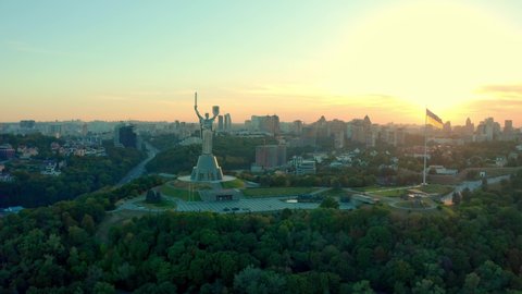 Aerial view to the Motherland statue in the Kiev while a beautiful summer sunset. Ukraine. 2020 year. Monument of the Motherland in Kiev. Flying a drone around famous monument in Ukraine Motherland. 