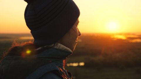 a lonely happy man stood and watched sunrise. free tourist woman looking at sun enjoying landscape. girl traveler with backpack stands on top of mountain in rays of sunset. hiker is enjoying nature.