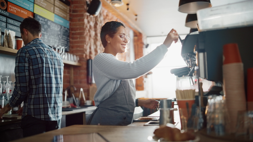 Beautiful Latin American Female Barista with Short Hair and Glasses is Making a Cup of Tasty Cappuccino in Coffee Shop Bar. Portrait of Happy Employee Behind Cozy Loft-Style Cafe Counter. | Shutterstock HD Video #1062664414