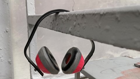 Footage of used earmuff hanging on iron angle bar in factory.
